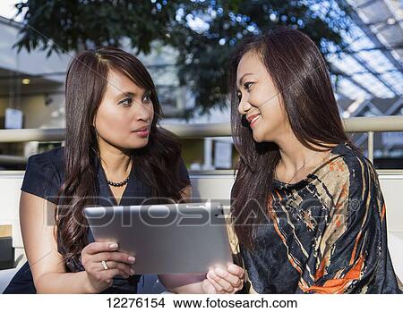 Picture - Businesswoman training a co-worker in a cafeteria at a shopping complex; St. Albert, Alberta, Canada. Fotosearch