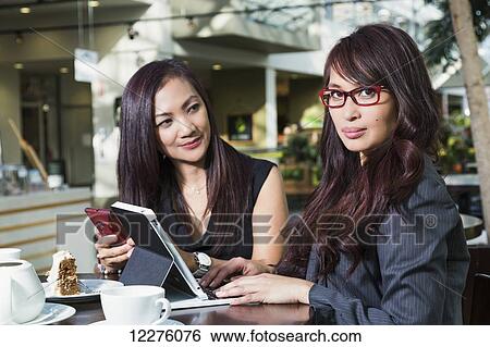 Businesswoman training a co-worker in a coffee shop at a shopping complex; St. Albert, Alberta, Canada View Large Photo Image Stock Photograph - Businesswoman training a co-worker in a coffee shop at a shopping complex; St. Albert, Alberta, Canada. Fotosearch