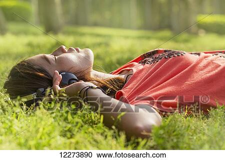 Chinese girl listening to music on the grass; Xiamen, Fujian Province, China View Large Photo Image Stock Image - Chinese girl listening to music on the grass; Xiamen, Fujian Province, China. Fotosearch