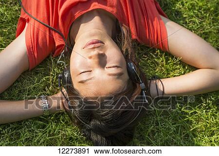 Stock Image - Chinese girl listening to music on the grass; Xiamen, Fujian Province, China. Fotosearch
