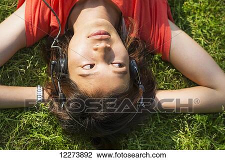 Stock Image - Chinese girl listening to music on the grass; Xiamen, Fujian Province, China. Fotosearch