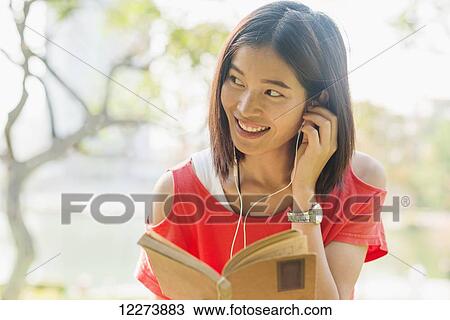 Chinese girl reading a book and listening to music; Xiamen, Fujian Province, China View Large Photo Image Stock Image - Chinese girl reading a book and listening to music; Xiamen, Fujian Province, China. Fotosearch