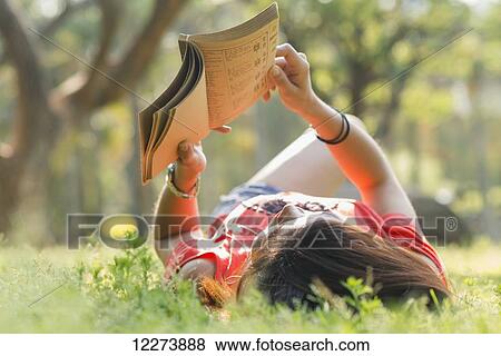 Stock Photo - Chinese girl reading a book and listening to music; Xiamen, Fujian Province, China. Fotosearch