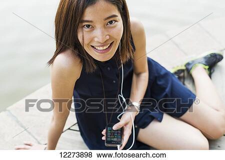 Stock Photo - Chinese girl smiling and listening to music; Xiamen, Fujian province, China. Fotosearch