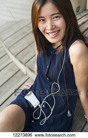 Stock Photograph - Chinese girl smiling and listening to music; Xiamen, Fujian province, China. Fotosearch