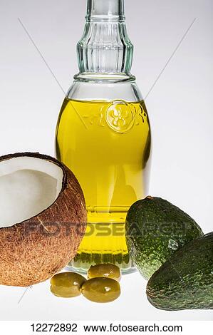 Stock Image - Close up of a coconut, olives, avocados, and glass bottle of olive oil on a white background; Calgary, Alberta, Canada. Fotosearch