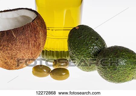 Stock Photo - Close up of a coconut, olives, avocados, and glass bottle of olive oil on a white background; Calgary, Alberta, Canada. Fotosearch