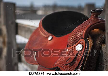 Picture - Close up of a saddle on a wooden fence; Regina, Saskatchewan, Canada. Fotosearch