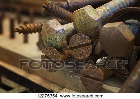 Close up of old, rusted screws and bolts in a pile sitting on a wooden board; United States of America View Large Photo Image Picture - Close up of old, rusted screws and bolts in a pile sitting on a wooden board; United States of America. Fotosearch