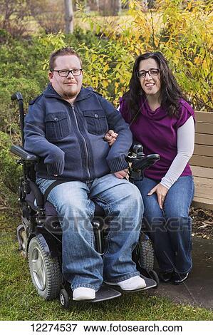 Stock Photo - Disabled husband and his wife posing for a family portrait in a park in autumn; Edmonton, Alberta, Canada. Fotosearch