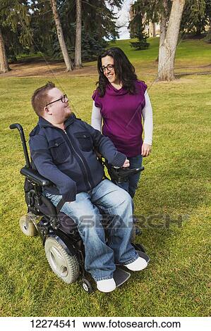 Stock Image - Disabled husband talking with his wife while walking in a park in autumn; Edmonton, Alberta, Canada. Fotosearch