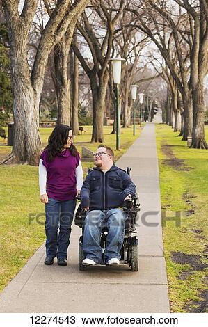 Stock Image - Disabled husband talking with his wife while walking in a park in autumn; Edmonton, Alberta, Canada. Fotosearch