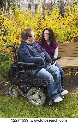 Stock Photo - Disabled husband talking with his wife on a park bench in autumn; Edmonton, Alberta, Canada. Fotosearch