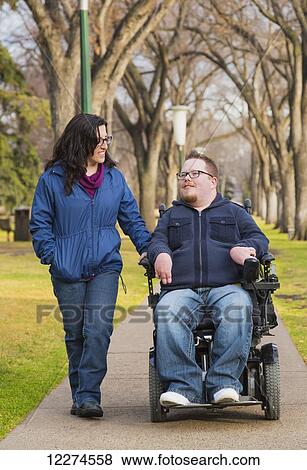 Stock Photo - Disabled husband talking with his wife while walking in a park in autumn; Edmonton, Alberta, Canada. Fotosearch