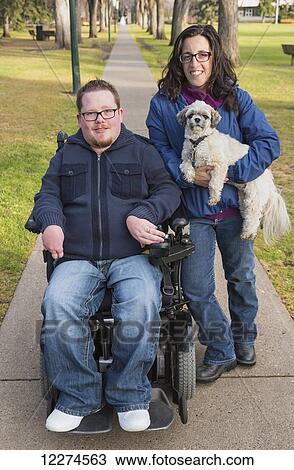 Disabled husband with his wife and their pet dog posing for a family portrait in a park in autumn; Edmonton, Alberta, Canada View Large Photo Image Stock Image - Disabled husband with his wife and their pet dog posing for a family portrait in a park in autumn; Edmonton, Alberta, Canada. Fotosearch