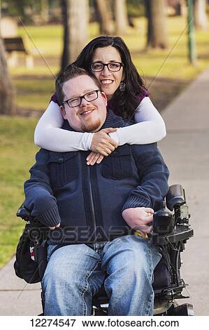 Stock Photo - Disabled husband with his wife posing for a picture in a park in autumn; Edmonton, Alberta, Canada. Fotosearch