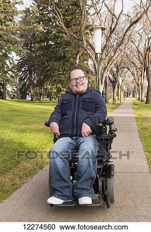 Stock Image - Disabled man using his powered wheelchair in a park in autumn; Edmonton, Alberta, Canada. Fotosearch