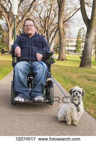 Stock Photo - Disabled man walking his dog in a park in autumn; Edmonton, Alberta, Canada. Fotosearch