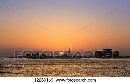 Stock Photo - Dramatic and colourful sunset over the harbour; Paphos, Cyprus. Fotosearch