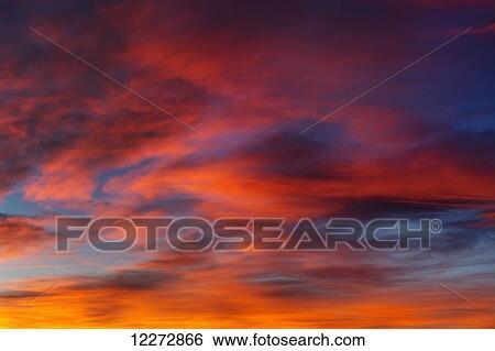 Stock Photograph - Dramatically colourful clouds at sunrise with blue sky; Calgary, Alberta, Canada. Fotosearch