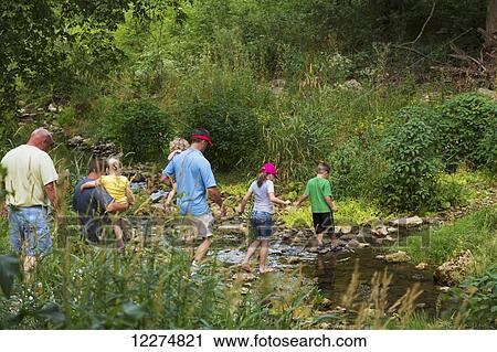 Stock Image - Family crossing Bear Creek on hiking trail leading to the Ice Cave at Bixby State Preserve, near Edgewood; Iowa, United States of America. Fotosearch