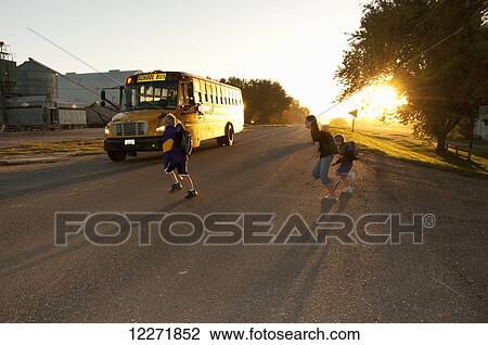 Farm children cross a country road to board a waiting school bus in early morning autumn light, near Sioux City; Iowa, United States of America View Large Photo Image Stock Image - Farm children cross a country road to board a waiting school bus in early morning autumn light, near Sioux City; Iowa, United States of America. Fotosearch