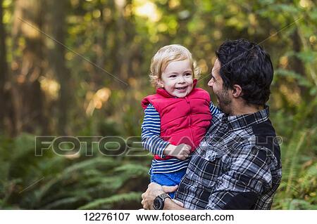 Father holding his son on a path in a rainforest; Langley, British Columbia, Canada View Large Photo Image Stock Photo - Father holding his son on a path in a rainforest; Langley, British Columbia, Canada. Fotosearch