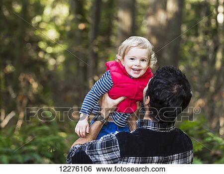 Stock Photograph - Father holding his son on a path in a rainforest; Langley, British Columbia, Canada. Fotosearch