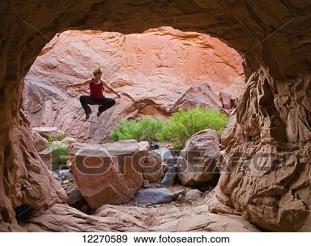 Stock Photo - Female adventurer jumping in a slot canyon; Hanksville, Utah, United States of America. Fotosearch