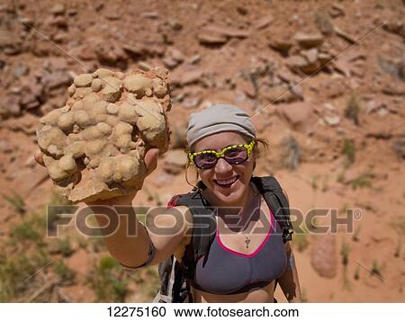 Stock Image - Female adventurer with a desert rock sample; Hanksville, Utah, United States of America. Fotosearch