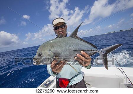 Stock Image - Fisherman holding a fresh caught Jackfish; Tahiti. Fotosearch