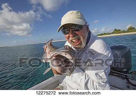 Stock Image - Fisherman holding a fresh caught Grouper; Tahiti. Fotosearch