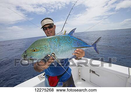 Stock Photo - Fisherman holding a fresh caught Jackfish tuna; Tahiti. Fotosearch