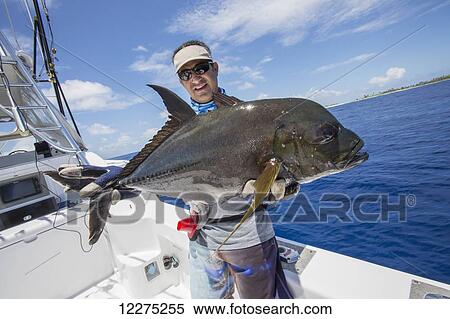 Stock Photography - Fisherman holds a fresh caught Jack Fish; Tahiti. Fotosearch