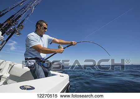 Stock Photography - Fishing for tuna off the Atlantic coast, with the rod bent while fighting the tuna; Massachusetts, United States of America. Fotosearch
