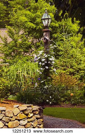 Stock Image - Flower garden and lamp post; Knowlton, Quebec, Canada. Fotosearch