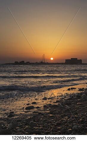 Stock Photography - Glowing orange and yellow sky at sunset over a mediterranean coastline; Paphos, Cyprus. Fotosearch