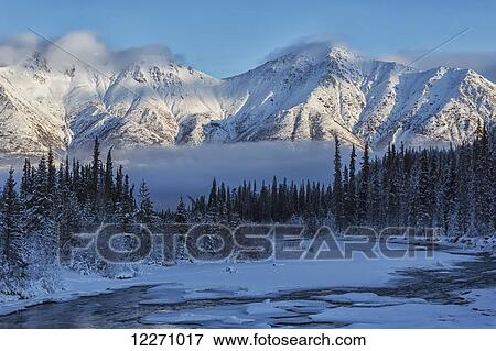 Stock Photo - Grey ridge looms over the Wheaton River near Whitehorse; Yukon, Canada. Fotosearch