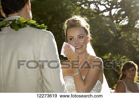Stock Photo - Happy bride during wedding ceremony wiping tears of joy; Hawaii, United States of America. Fotosearch
