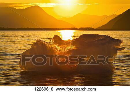 Iceberg glows in gold at sunset, Portage Glacier, Kenai Peninsula; Alaska, United States of America View Large Photo Image Stock Photo - Iceberg glows in gold at sunset, Portage Glacier, Kenai Peninsula; Alaska, United States of America. Fotosearch