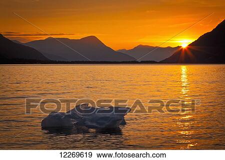 Stock Photo - Iceberg glows in gold at sunset, Portage Glacier, Kenai Peninsula; Alaska, United States of America. Fotosearch