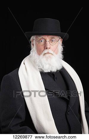 Stock Photo - Mature bearded Jewish man wearing spectacles, hat, overcoat and a scarf; Alberta, Canada. Fotosearch
