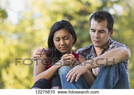 Stock Image - Mixed race couple praying together in a park in autumn; St. Albert, Alberta, Canada. Fotosearch