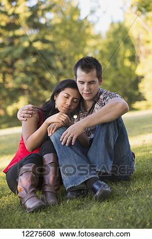 Stock Photo - Mixed race couple praying together in a park in autumn; St. Albert, Alberta, Canada. Fotosearch