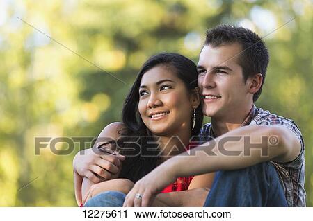 Stock Image - Mixed race couple spending quality time together in a park in autumn; St. Albert, Alberta, Canada. Fotosearch