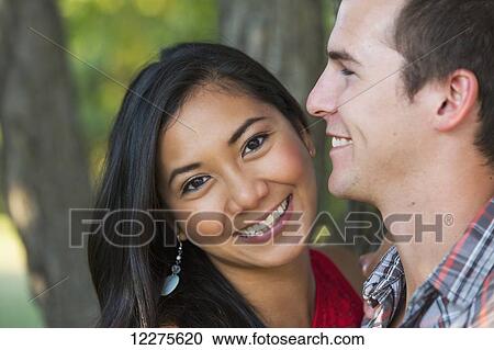 Stock Image - Mixed race couple spending quality time together in a park in autumn; St. Albert, Alberta, Canada. Fotosearch