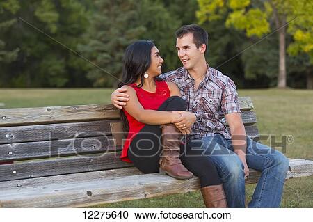 Stock Image - Mixed race couple spending quality time together in a park in autumn; St. Albert, Alberta, Canada. Fotosearch