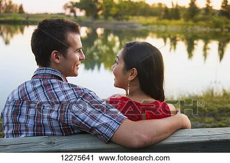 Stock Image - Mixed race couple spending quality time together in a park in autumn; St. Albert, Alberta, Canada. Fotosearch