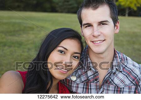 Stock Image - Mixed race couple spending quality time together in a park in autumn; St. Albert, Alberta, Canada. Fotosearch