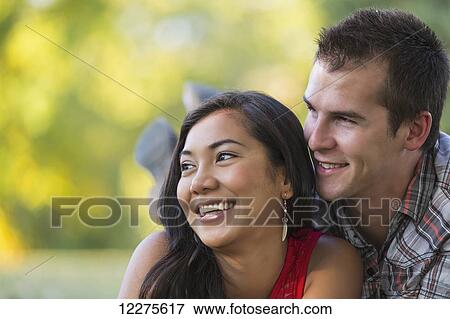 Stock Photo - Mixed race couple spending quality time together in a park in autumn; St. Albert, Alberta, Canada. Fotosearch